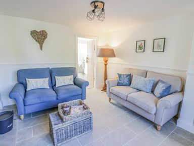 A sitting room with two sofas a floor lamp and wicker baskets at Blossom Cottage in Broadway
