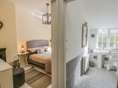 A bedroom with a bed and a side table next to a bathroom with a sink and a toilet at Blossom Cottage in Broadway