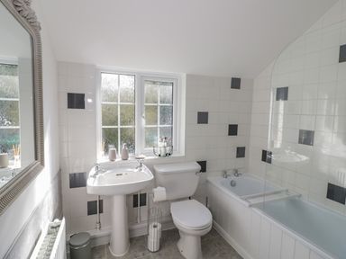 A bathroom with a pedestal sink toilet and bathtub with tiled walls at Blossom Cottage in Broadway