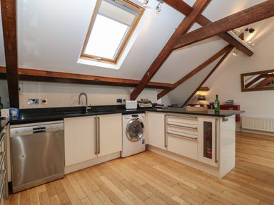 A kitchen with wooden beams a skylight dishwasher washing machine and a countertop at Apartment 2 Gorwel Glas in Llanbedrog