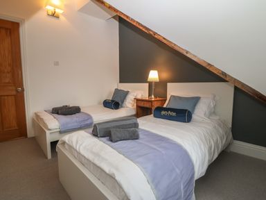 A bedroom with two single beds next to a wooden nightstand with a lamp at Apartment 2 Gorwel Glas in Llanbedrog