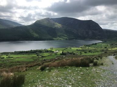 A landscape with a lake surrounded by mountains and green fields at Apartment 2, Gorwel Glas in Llanbedrog