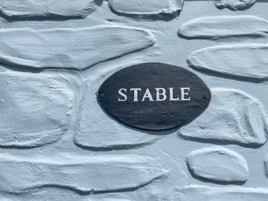 A black oval sign with the word stable on a textured light blue wall at The Stable @ Canllefaes Penparc near Cardigan