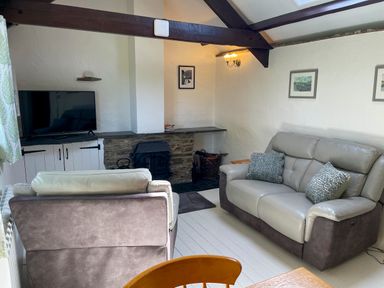 A living room with two sofas a television and a fireplace at The Stable @ Canllefaes Penparc near Cardigan