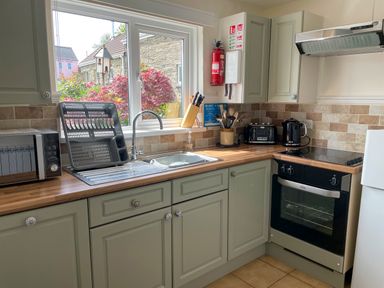 A kitchen with stove microwave kettle and toaster under a window at The Stable @ Canllefaes in Penparc near Cardigan