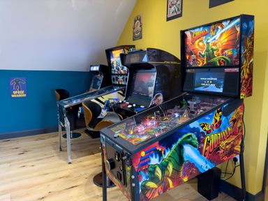A room with a Godzilla pinball machine a Star Wars arcade game and other arcade machines with chairs at The Stable @ Canllefaes in Penparc near Cardigan
