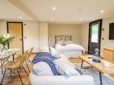 A room with a bed a sofa table with chairs and a door at The Cabin at Evelyns Retreat in Glyndyfrdwy
