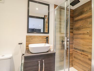 A bathroom with a sink cabinet mirror shower and toilet at The Cabin at Evelyns Retreat in Glyndyfrdwy