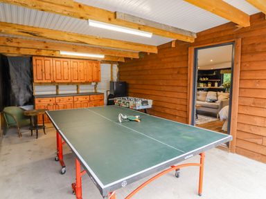 A recreational room with a ping pong table foosball table cabinets and a chair at The Cabin at Evelyns Retreat in Glyndyfrdwy