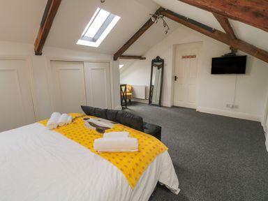 A bedroom with a bed and towels a chair and a mirror under a skylight at The Wizard's Loft in Alnwick