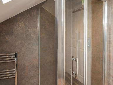 A bathroom with a glass shower enclosure and a chrome towel rack at The Wizard's Loft in Alnwick