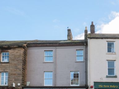 The upper floors of three connected buildings with windows under a blue sky at The Wizards Loft in Alnwick