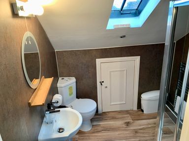 A bathroom with a sink mirror toilet skylight window and small door at The Wizard's Loft in Alnwick