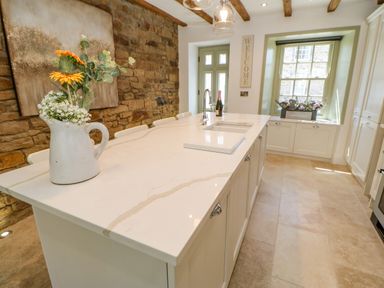 A kitchen with a marble island countertop and a vase with flowers on the island at Bramwell House in Corbridge