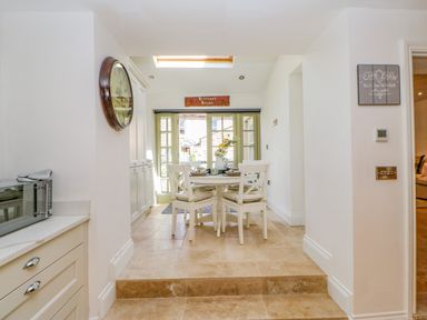 A dining area with a round table and four chairs near glass doors at Bramwell House Corbridge