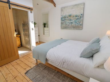 A bedroom with a bed a rug a wooden sliding door and a white chest of drawers at Bramwell House in Corbridge