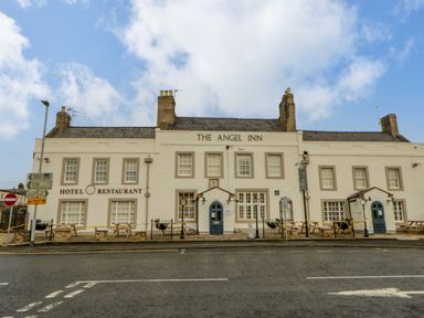 The exterior of The Angel Inn with signs for hotel and restaurant and outdoor seating at Bramwell House in Corbridge