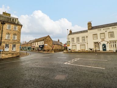 A street intersection with old stone buildings including The Angel Inn hotel and restaurant at Bramwell House in Corbridge