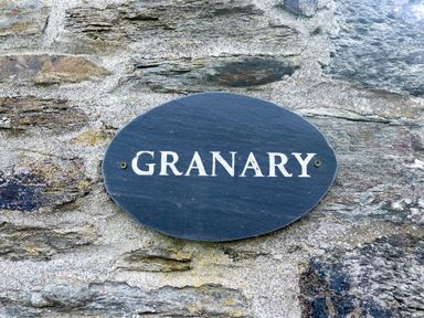 A stone wall with a dark oval plaque reading GRANARY at The Granary @ Canllefaes in Penparc near Cardigan