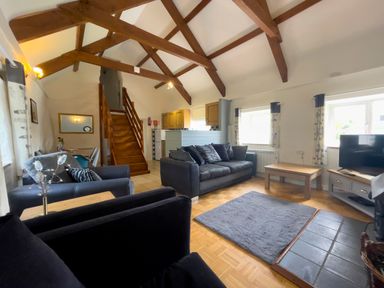 A living room with sofas a coffee table and a TV near windows and stairs at The Granary @ Canllefaes in Penparc near Cardigan