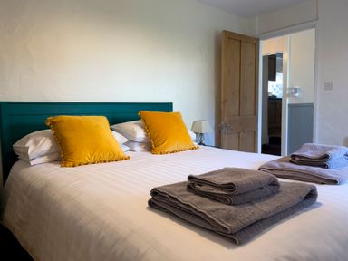 A bedroom with a bed with yellow pillows and folded towels on it at The Granary @ Canllefaes in Penparc near Cardigan