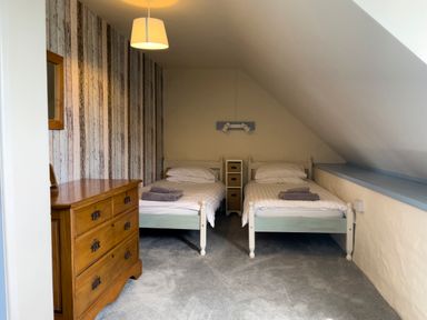 A bedroom with two single beds and a wooden chest of drawers at The Granary @ Canllefaes in Penparc near Cardigan
