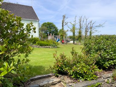 A garden with bushes and trees a playground with a slide and a large chess set at The Granary @ Canllefaes in Penparc near Cardigan
