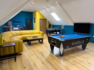 A game room with a yellow sectional sofa a pool table a foosball table and a television at The Granary @ Canllefaes Penparc near Cardigan
