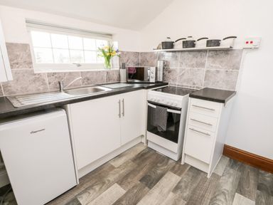 A kitchen with a sink microwave stove pots and drawers at Hawthorn Dale Cottage in Whitby