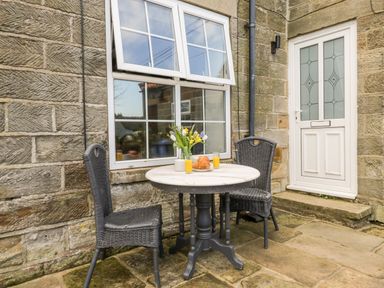 An outdoor seating area with a round table with flowers croissants and juice and two chairs at Hawthorn Dale Cottage in Whitby