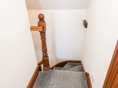 A staircase with gray carpet and wooden handrail at Hawthorn Dale Cottage in Whitby