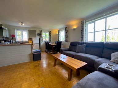An open living space with a dining table, kitchen area, sofa, and coffee table at The Wheel @ Canllefaes in Penparc near Cardigan