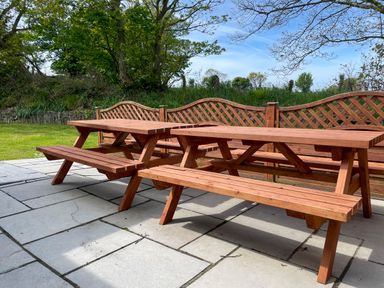 A patio with two wooden picnic tables and wooden lattice fencing at The Wheel @ Canllefaes in Penparc near Cardigan
