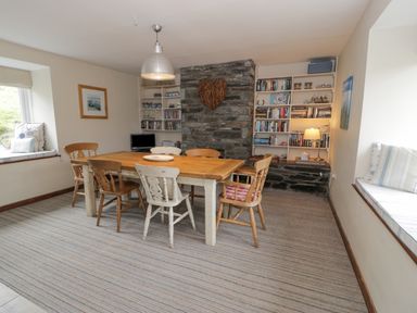 A dining room with a wooden table and chairs a stone chimney and built in shelves at Pennant Tigi Uchaf in Dinas Mawddwy