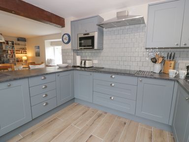 A kitchen with blue cabinets a microwave toaster and kitchen utensils at Pennant Tigi Uchaf in Dinas Mawddwy