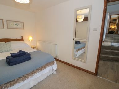A bedroom with a bed a bedside lamp and a wall mirror at Pennant Tigi Uchaf in Dinas Mawddwy