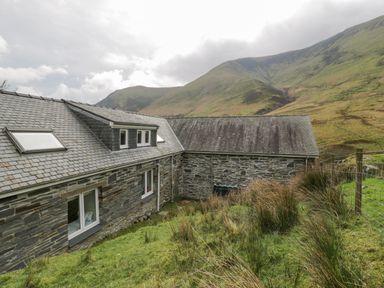 Stone houses with slate roofs near grassy hillside and mountains at Pennant Tigi Uchaf in Dinas Mawddwy