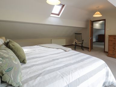 A bedroom with a bed pillows chair chest of drawers and a skylight window at Pennant Tigi Uchaf in Dinas Mawddwy