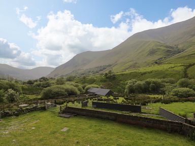 A rural landscape with green fields trees and mountains in the background at Pennant Tigi Uchaf in Dinas Mawddwy