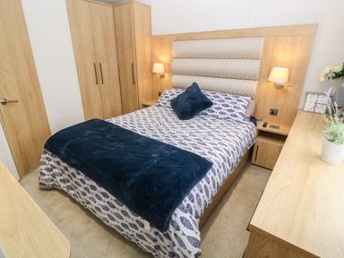 A bedroom with a double bed a chest of drawers and wardrobes at Chantry Lodge in Hendra Croft near Goonhavern