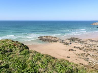 A coastal view with sandy beach rocky formations and ocean waves at Chantry Lodge in Hendra Croft near Goonhavern