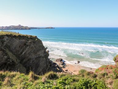 A coastal landscape with cliffs, beach, and ocean waves at Chantry Lodge in Hendra Croft near Goonhavern