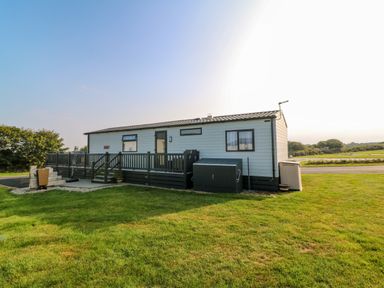 Exterior view of a single-story mobile home with a porch and railing on a grassy lawn at Chantry Lodge in Hendra Croft near Goonhavern