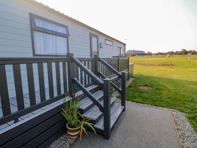 Exterior view of a mobile home with steps and railing leading to a door and a potted plant at Chantry Lodge in Hendra Croft near Goonhavern