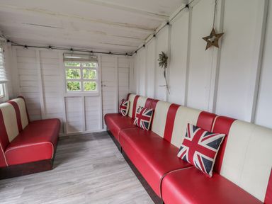 A small room with red and white striped benches and Union Jack pillows at Wyvill House in Cayton