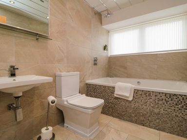 A bathroom with a bathtub, toilet, and sink at Wyvill House in Cayton