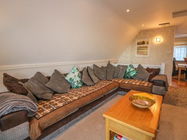 A living room with a large sectional sofa and wooden coffee table at Hillside in Gunnislake
