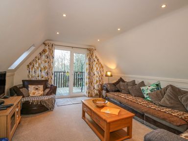 A living room with a sofa armchair coffee table TV and balcony doors at Hillside in Gunnislake
