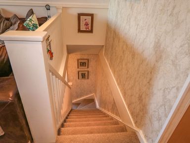 A carpeted staircase with white railing and patterned wallpaper at Hillside in Gunnislake