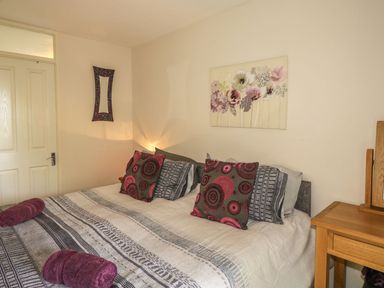 A bedroom with a bed with patterned pillows and a striped bedspread at Hillside in Gunnislake